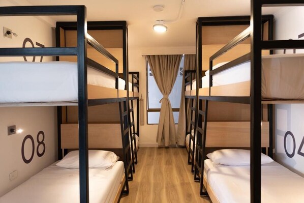 A room with bunk beds, numbered 08 and 04, wooden flooring, and a window with curtains. - Casana Rosa Hotel (Santa Marta)