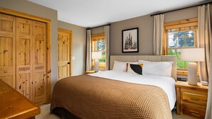 Een slaapkamer met een groot bed, een houten garderobe en een raam met gordijnen.