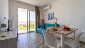 Ein modernes Wohnzimmer mit Essbereich, einer Couch, einem Fernseher und einem Gemälde an der Wand.