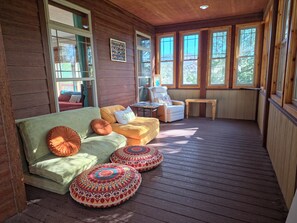Une terrasse en bois avec un canapé et des poufs, une chaise et une table.
