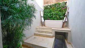 Un espace de bien-être comprenant une baignoire, des marches et une végétation luxuriante.