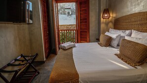Une chambre à coucher avec un lit, une télévision et un balcon doté de volets en bois.