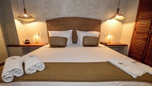 Un lit bien fait, avec une tête de lit marron, deux tables de chevet avec des lampes et une porte en bois.