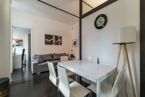 A modern living room with a white table, grey sofa, and a painting on the wall.