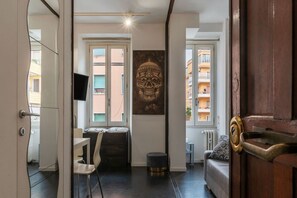 A room with a desk, chair, sofa, and a large skull artwork on the wall.