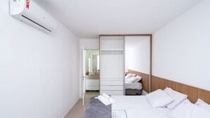 Et hotelværelse med en seng, et natbord, et spejl, et klædeskab og en aircondition.