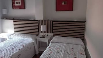 Une chambre d’hôtel avec deux lits, une table de chevet avec une lampe et deux tableaux encadrés au mur.