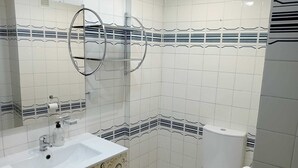 A bathroom with a white sink, mirror, toilet, and patterned tiles.