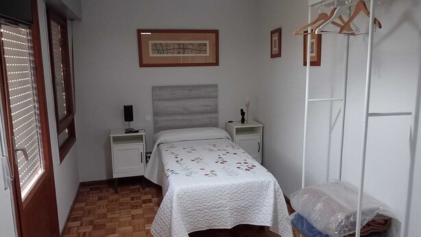 A bedroom with a bed, two bedside tables, a wardrobe, and a framed picture on the wall.
