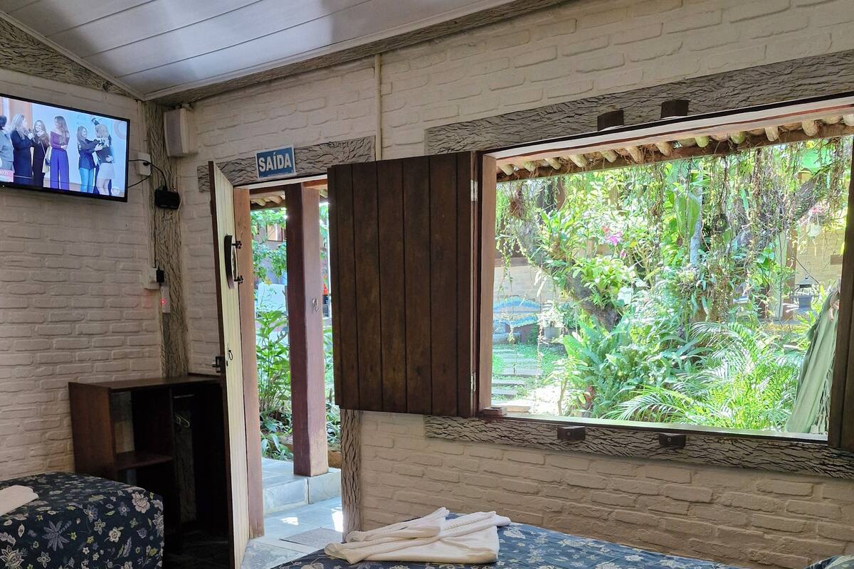 Una habitación con dos camas, televisión y vista al verdor exterior.