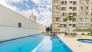 Una piscina con sillas de descanso y un edificio blanco al fondo.