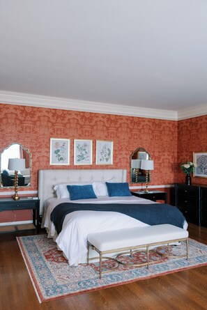 Une chambre à coucher avec un grand lit, deux tables de chevet, un banc et un tapis à motifs.