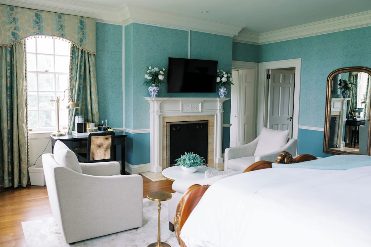Une chambre d’hôtel équipée d’une cheminée, d’une télévision, d’un lit, d’un canapé et d’un bureau.