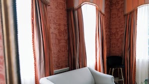 A room with a white sofa, a black chair, a patterned rug, and curtains with tassels. - Bohemia Manor Farm (Chesapeake City)
