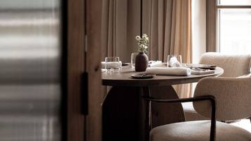 A dining area with a table set for two, a vase of flowers, and a pendant light.