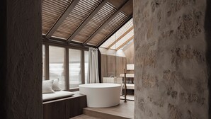 A modern bathroom with a large bathtub, wooden beams, and a view of the beach. - stieg'nhaus Design Boutique Hotel (Muehlbach Am Hochkoenig)