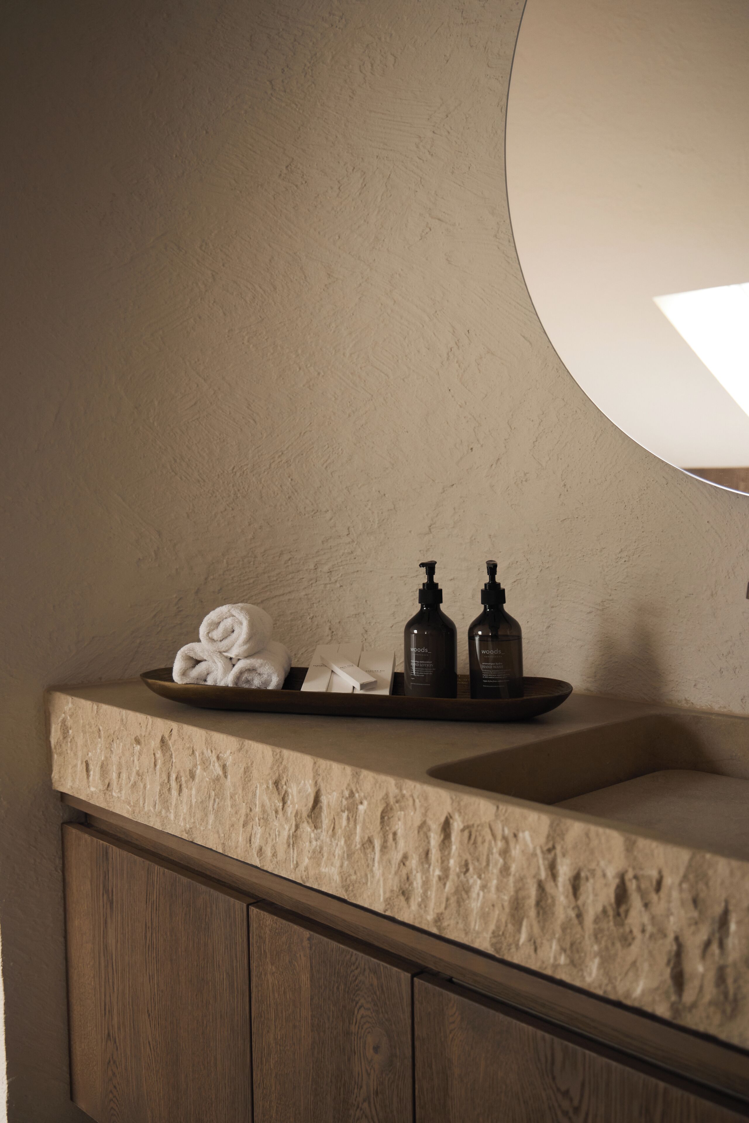 A bathroom with a stone countertop, a wooden cabinet, and a mirror.