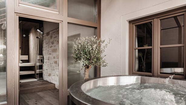 A spa area with a hot tub, wooden flooring, and a glass door leading to a shower area. - stieg'nhaus Design Boutique Hotel (Muehlbach Am Hochkoenig)
