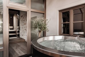A spa area with a hot tub, wooden flooring, and a glass door leading to a shower area. - stieg'nhaus Design Boutique Hotel (Muehlbach Am Hochkoenig)