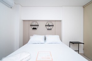 A hotel room with a bed, two hexagonal shelves on the wall, a small table, and a door. - Apartments in Jardim Goias Goiania/go - THO (Goiânia)