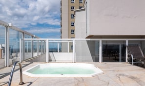 A rooftop pool with a glass enclosure, a lounge chair, and a view of the cityscape. - Apartments in Jardim Goias Goiania/go - THO (Goiânia)