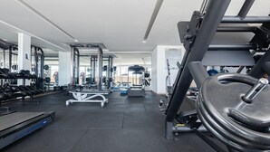 Un gimnasio con equipo de ejercicio, cinta de correr y pared espejada.
