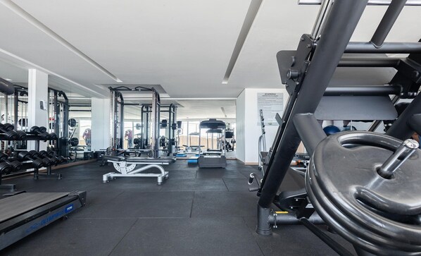 A gym with exercise equipment, a treadmill, and a mirrored wall. - Apartments in Jardim Goias Goiania/go - THO (Goiânia)
