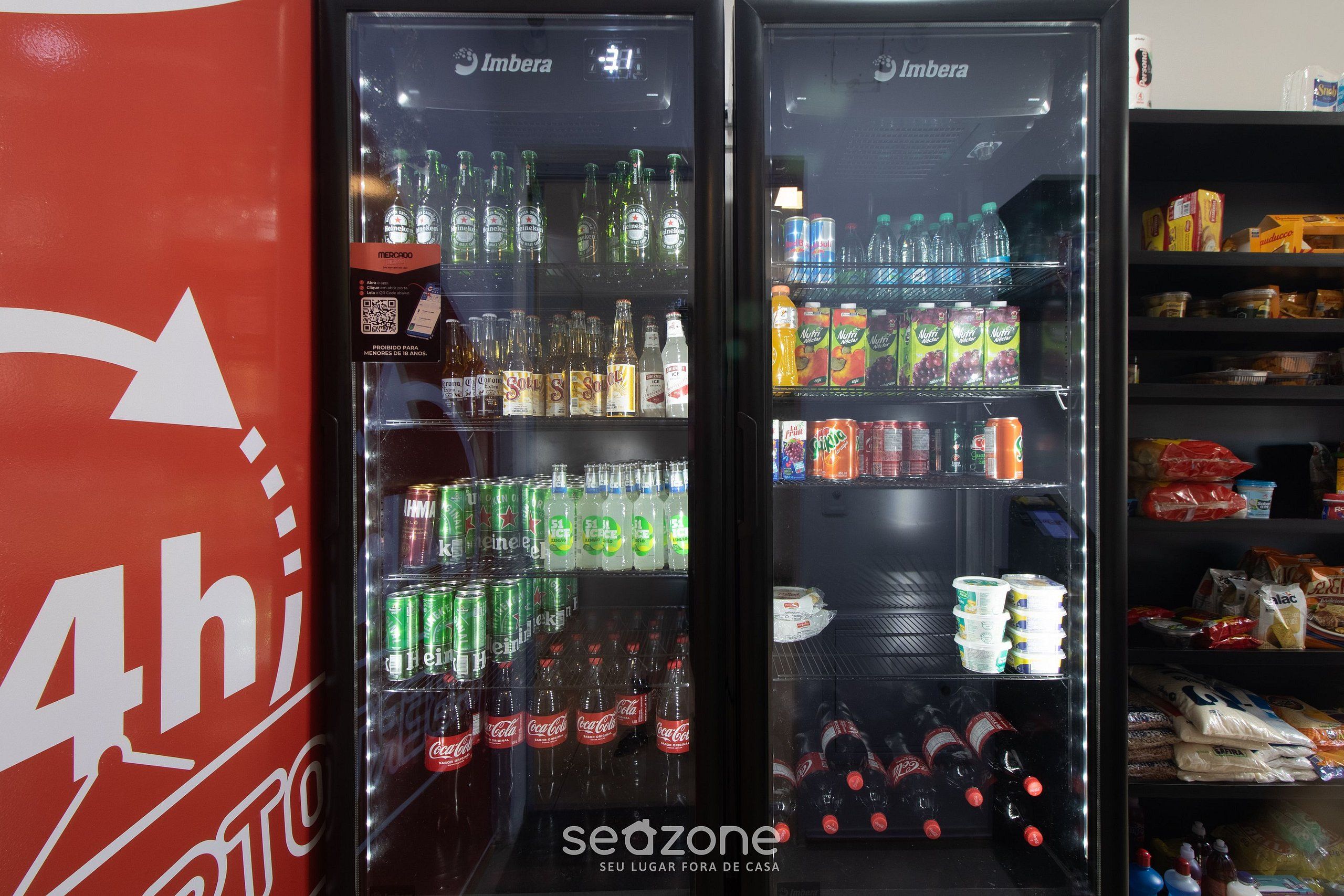 Two refrigerated beverage dispensers stocked with various drinks, including sodas and bottled water, in a commercial setting.