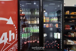 Deux distributeurs de boissons réfrigérés, remplis de diverses boissons, notamment des sodas et de l’eau en bouteille, dans un établissement commercial.