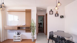 A modern living room with a dining area, a potted plant, and a wooden shelf unit. - Apt in Full Condo, St. Faicalville - Vam0504 (Goiânia)