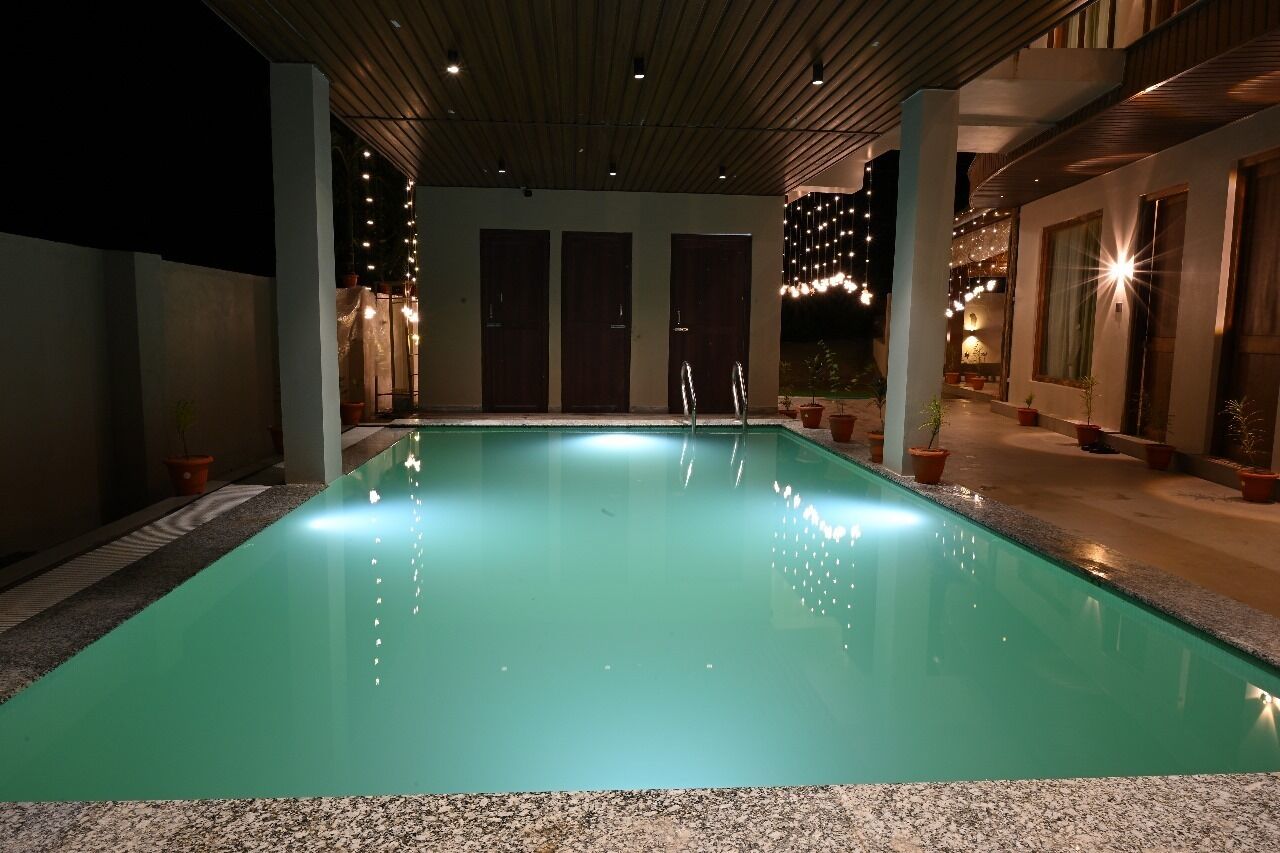 A swimming pool with a clear water surface, surrounded by potted plants and a wooden ceiling structure.