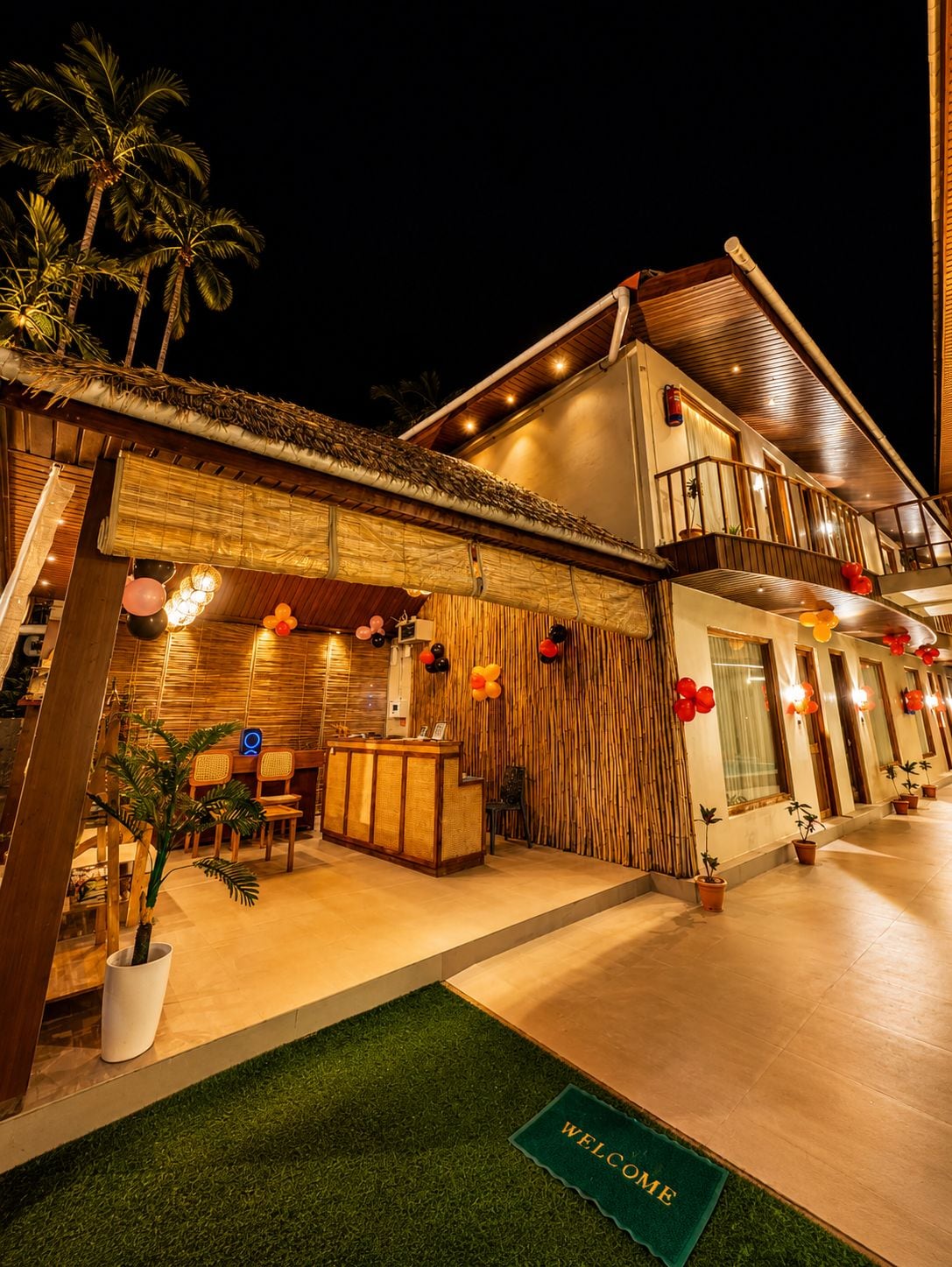 A hotel with a reception desk, a balcony, and a well-lit entrance.