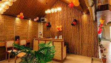 A reception area with a wooden reception desk, wicker chairs, and a bamboo wall.