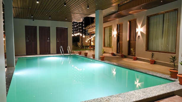 A swimming pool with a clear blue water surface, surrounded by potted plants and wooden doors. - The Elysian Boutique Stays (Port Blair)