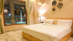 A neatly made bed with white linens, a wooden headboard, and a nightstand with a lamp. - The Elysian Boutique Stays (Port Blair)