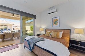 Ein Hotelzimmer mit einem Bett, einem Nachttisch, einer Lampe, einem Bild an der Wand und Blick auf die Terrass.