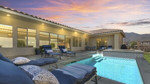 Une maison moderne dotée d’une piscine, d’un espace salon extérieur et de grandes fenêtres.