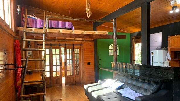 A cozy cabin with a loft bed, a sofa, and a dining area. - URBAN CABIN - DOWNTOWN OF CASCAVEL. (Country Cascavel)