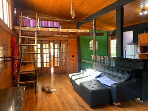 A cozy cabin with a loft bed, a sofa, and a dining area. - URBAN CABIN - DOWNTOWN OF CASCAVEL. (Country Cascavel)