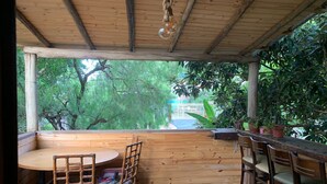 A wooden deck with a round table and chairs, surrounded by potted plants. - URBAN CABIN - DOWNTOWN OF CASCAVEL. (Country Cascavel)