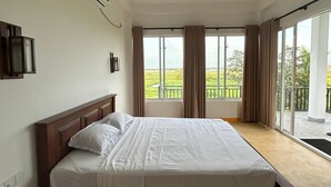 A bedroom with a large bed, an air conditioning unit, a ceiling fan, and a view of a balcony with curtains. - Neralu Garden Yala  (Tissamaharama)