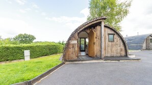 Una estructura de madera con techo curvo, una puerta y una ventana pequeña.