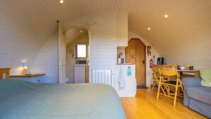 Un dormitorio acogedor en el ático, con cama, un pequeño rincón de cocina y zona de comedor.
