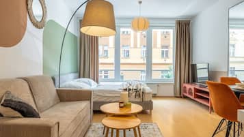 A modern hotel room with a sofa, a bed, a dining table, and a TV.