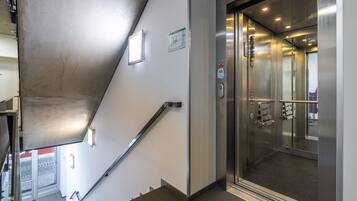 A modern elevator with stainless steel doors and a control panel.