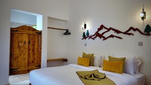 Un dormitorio con una cama grande, cabecera de madera y alfombra roja. Se observa un armario de madera y una lámpara fijada a la pared.