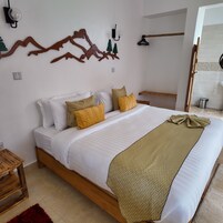 Un dormitorio con cama de madera, ropa de cama blanca y un adorno en la pared.