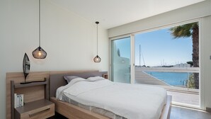 Un dormitorio moderno con una cama de madera, mesitas de noche y vistas al mar.