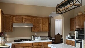 A kitchen with wooden cabinets, a gas stove, a toaster, and a built-in oven. - 4-bedroom pool house in Fresno, hub for all California destinations &attractions (Fresno)