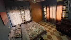 Ein Schlafzimmer mit Bett, Kleiderschrank, Sofa und Vorhängen.